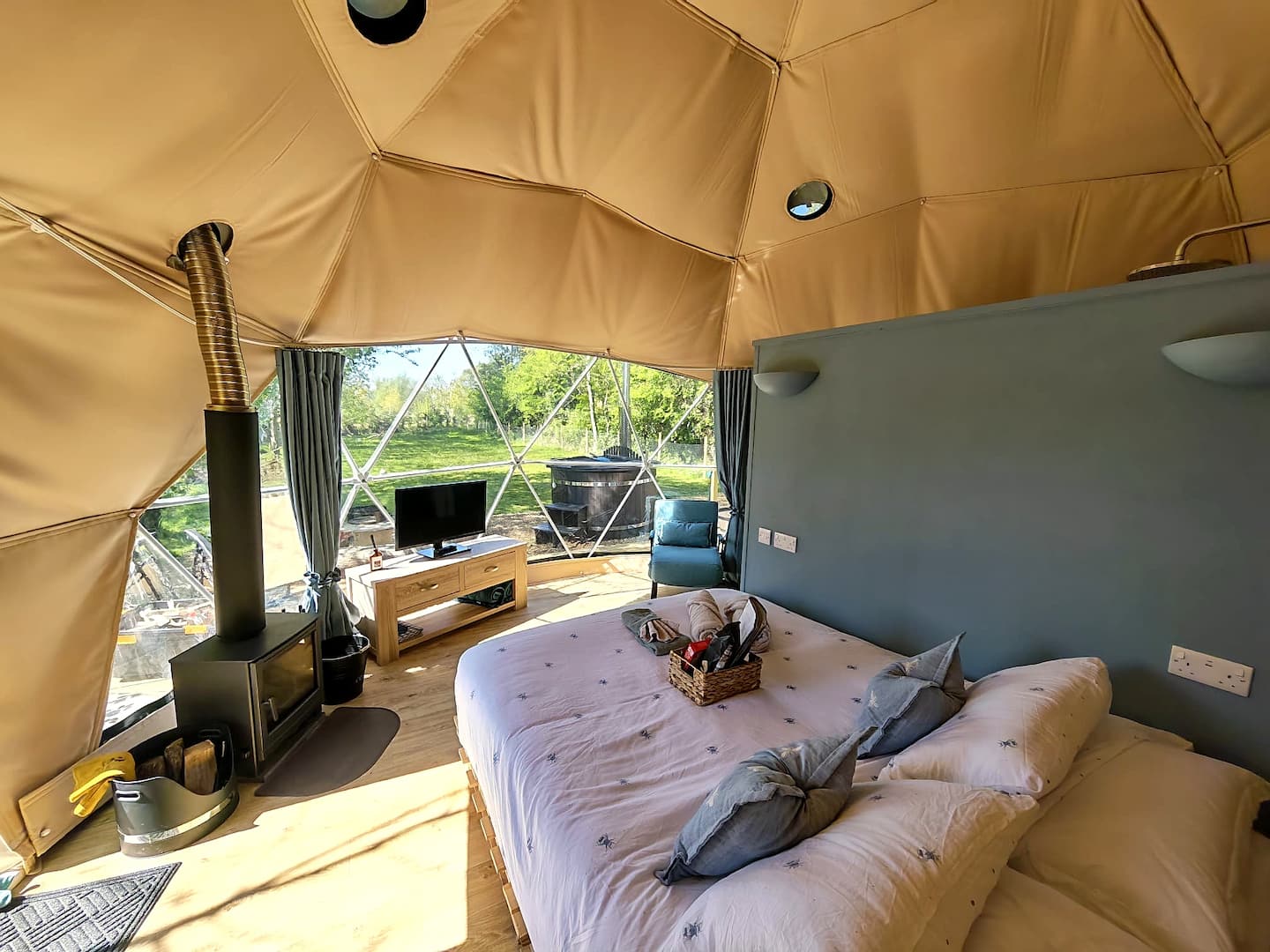 Cherry Tree interior with a wood burner, bed and panoramic window looking into the garden